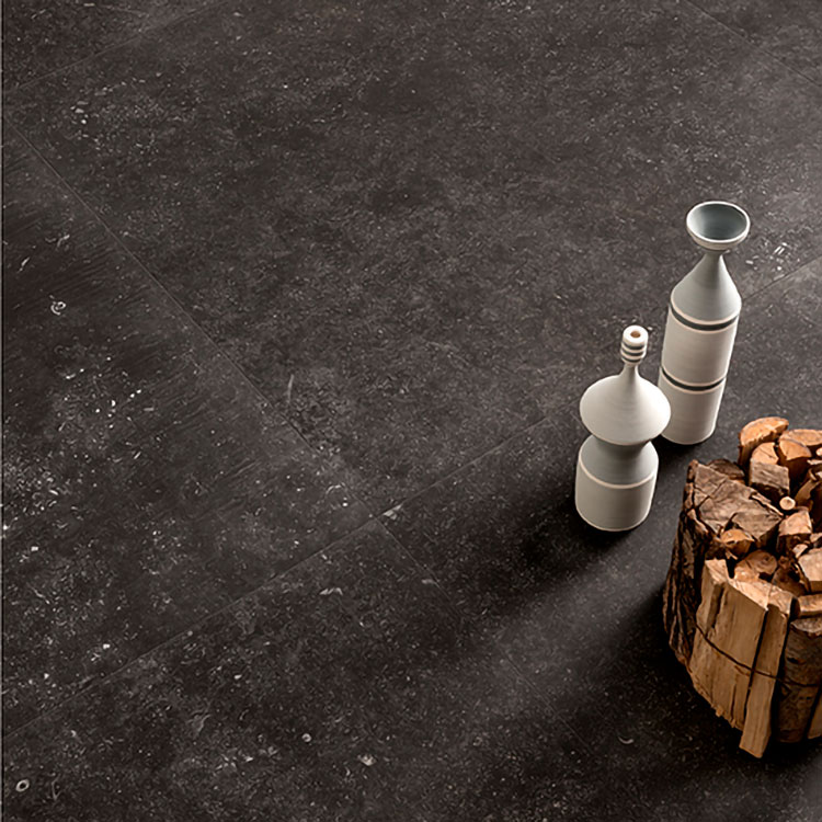 Copertina serie Belgica. Still life del pagimento nero con alcuni oggetti in ceramica e legna da ardere appoggiati sul pavimento.